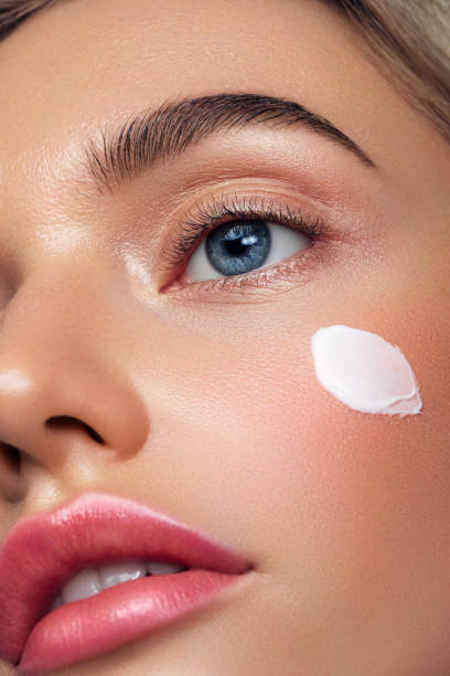 Portrait of beautiful young woman applying skin cream