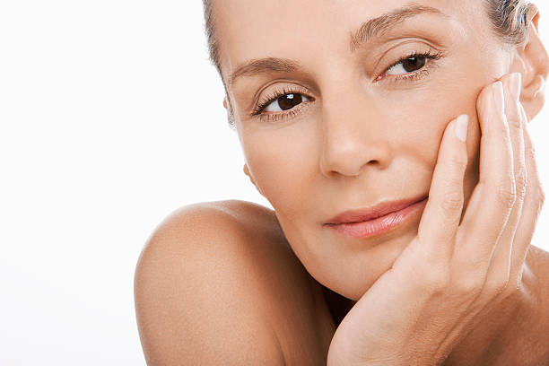 Closeup of relaxed middle aged woman with hand on chin over white background