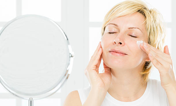 Middle aged woman with closed eyes cleaning her face.