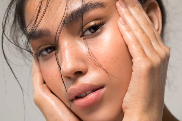 Close up studio shot of a beautiful young woman with perfect glow skin.