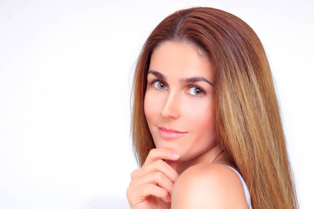 Beautiful woman's face smiles at the camera and touches her chin