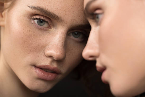 Beautiful emotional woman with natural make-up looking at the mirror